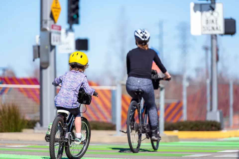 Mother and child on bicycles riding on green dedicated bike lane